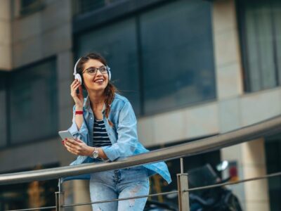 young-woman-listens-to-music-via-headphones-and-smartphone-in-the-city.jpg